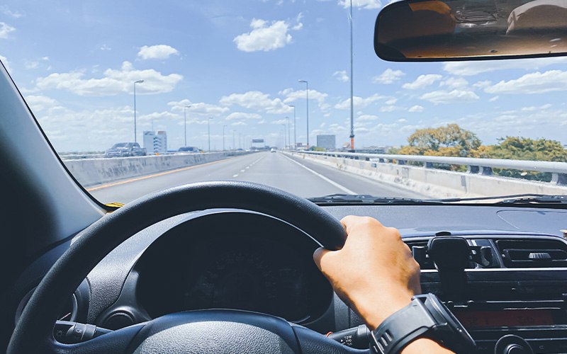 Driver's view of a car on a sunny overhead expressway.