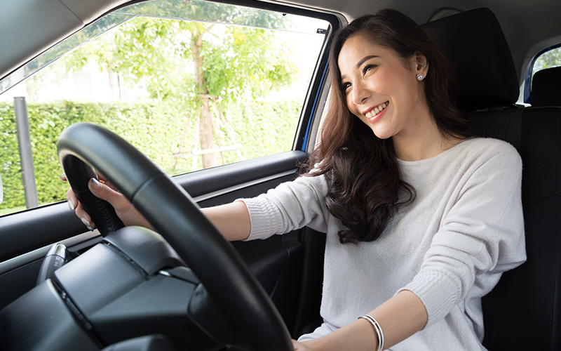 Person holding the steering wheel and smiling during a drive