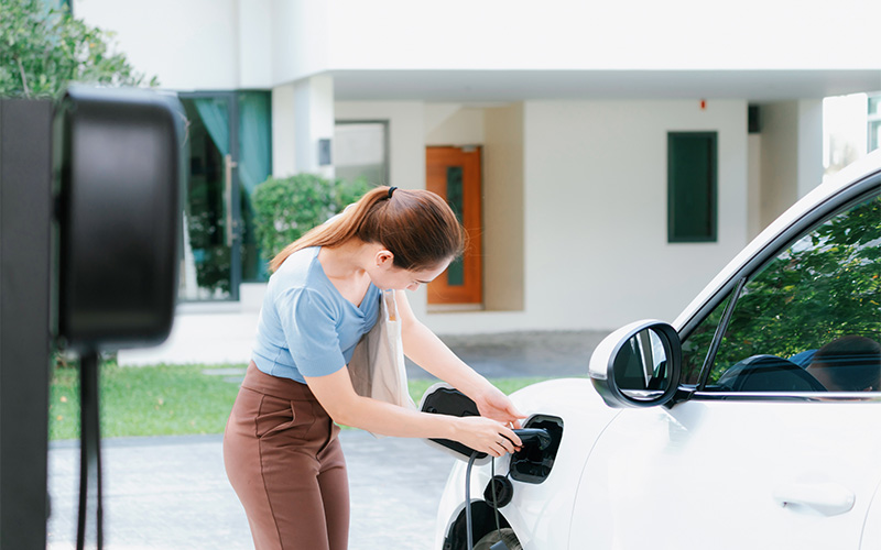 Smart driver charging her electric car at home.