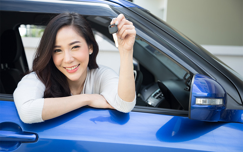 Woman celebrating new car, a benefit of car leasing in Singapore.